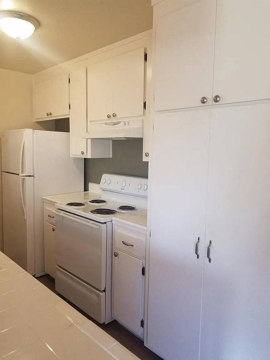 A white kitchen with a stove, oven, and refrigerator.